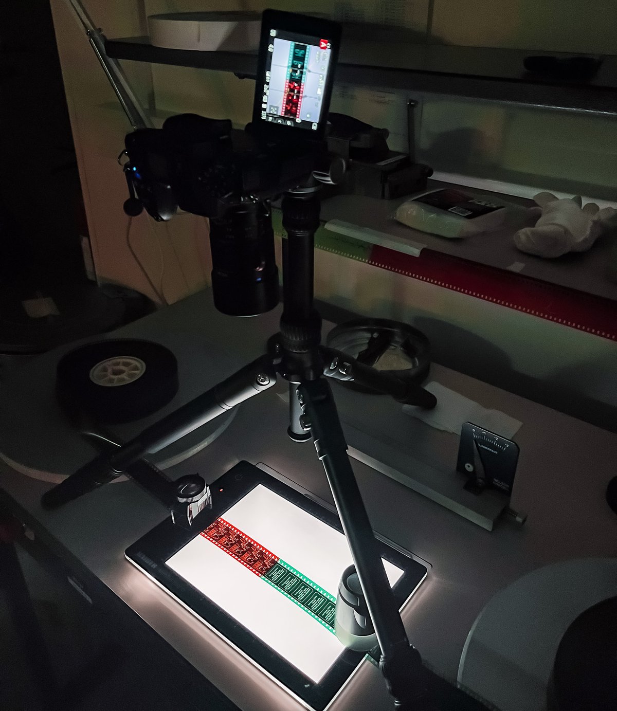 A photo showing a tripod with a camera, over a film inspection table A photo showing a tripod with a camera, over a film inspection table